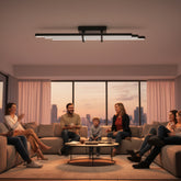 Modern bir salonda gün batımında geniş bir koltukta oturan ailenin üzerinde parlayan Cosmo Downlight Plafonyer aydınlatma sistemi