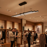 Lüks bir butik mağazada şık giyimli müşterilerin altında Cosmo Downlight modern lineer sarkıt avize.