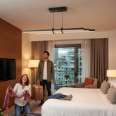 Lüks otel odasında Cosmo Downlight sarkıt avize altında bavullarını hazırlayan mutlu genç çift ve modern aydınlatma atmosferi.