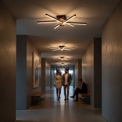 Modern bir apartman holünde Nova Eight aydınlatma eşliğinde sohbet eden çift ve dinlenen adam.
