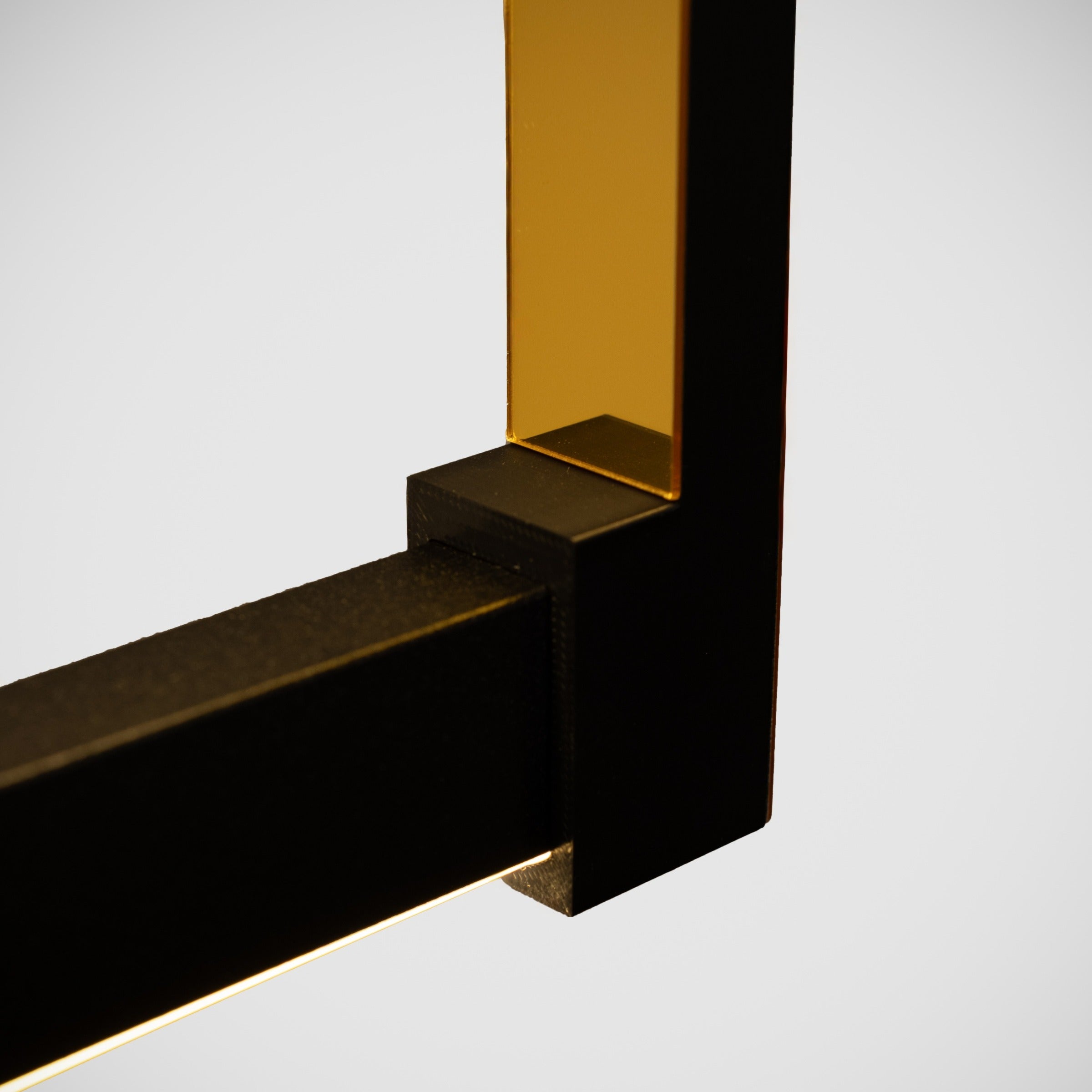 Lüks aydınlatma tasarımı Orion avizenin altın renkli dekoratif plakası ve pürüzsüz siyah metal finisajının makro görüntüsü.