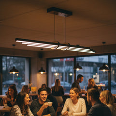 Modern cafe ortamında Cosmo Downlight linear sarkıt avize altında sohbet eden insanlar ve sıcak atmosfer.