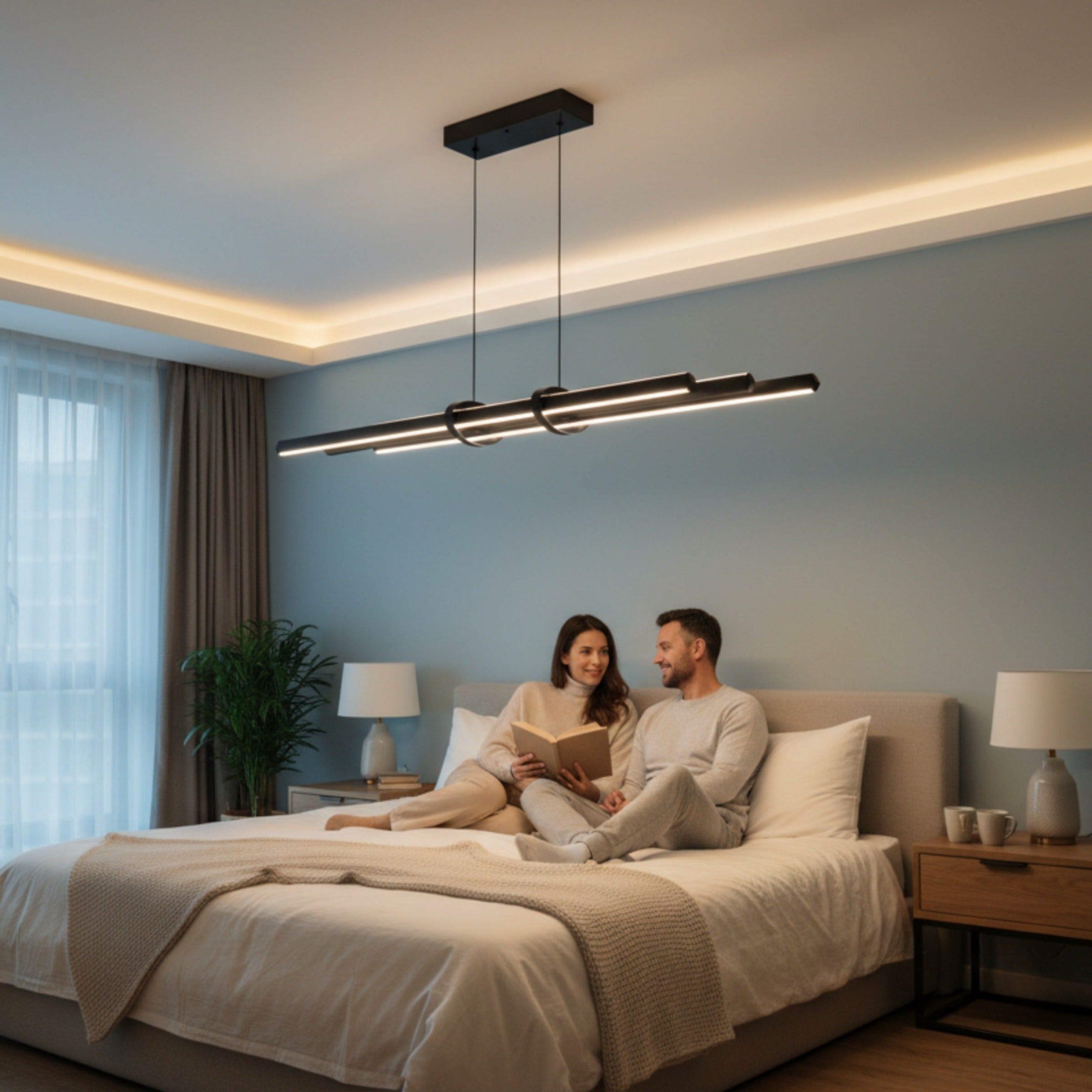 Modern bir yatak odasında yatakta kitap okuyan çiftin üzerinde süzülen Cosmo Up & Down mat siyah çift yönlü premium LED sarkıt avize.