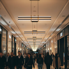 Kalabalık bir AVM koridorunda tavan boyunca sıralanan Halo modern lineer LED sarkıt avizelerin yarattığı görkemli atmosfer.